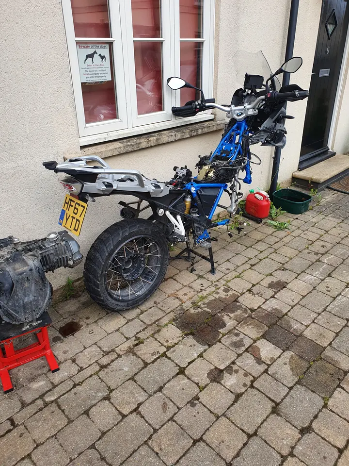 The motorcycle with its tank and bodywork removed during headlight access.